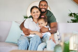 Family smiling together on a couch, showcasing a happy moment, emphasizing the importance of confidence and aesthetics in smiles.